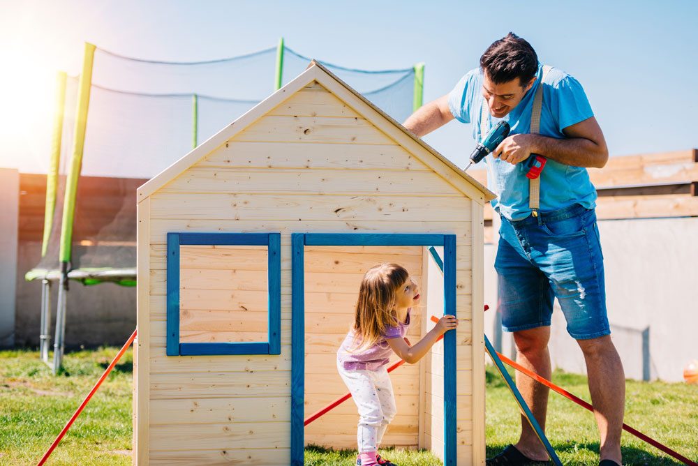 Vater baut mit Tochter Spielehaus für den Garten.