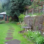 Teil eines Gartens mit Rasen und Mauerbepflanzung